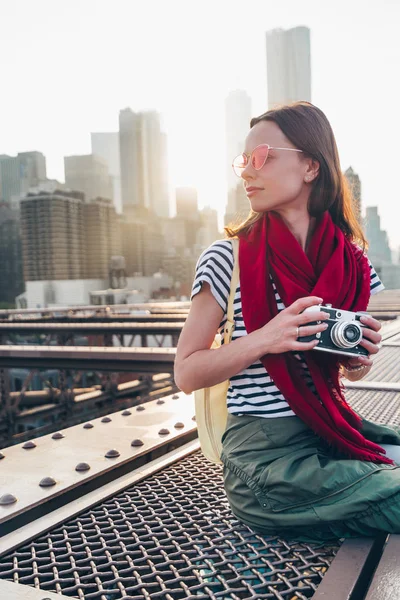 日出时在布鲁克林大桥上带着相机的年轻女孩 — 图库照片