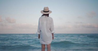 Deniz kenarındaki şapkalı genç kız, ağır çekimde.