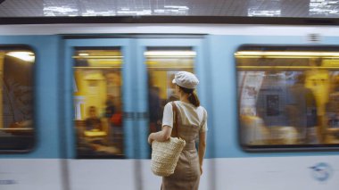 Paris metrosunda tren bekleyen genç bir kadın.