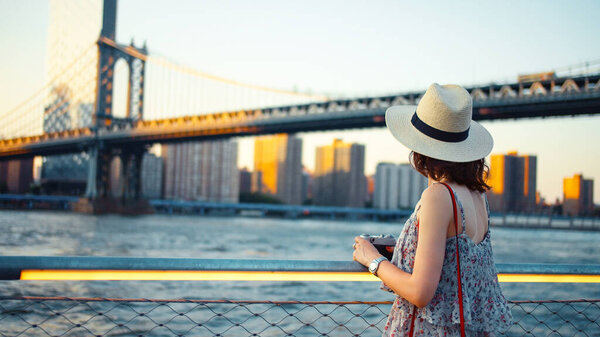 Young woman with a retro camera at the Manhattan Bridge in New York