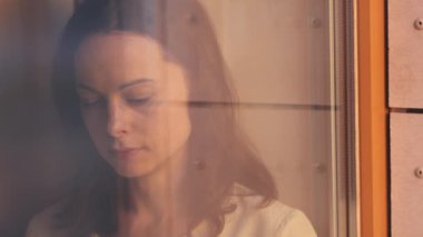 Pencerenin kenarında kitap okuyan genç bir kız, yakın plan.