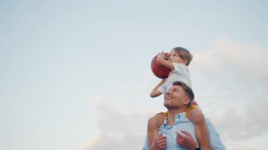 Babasıyla dışarıda basketbol oynayan küçük çocuk.
