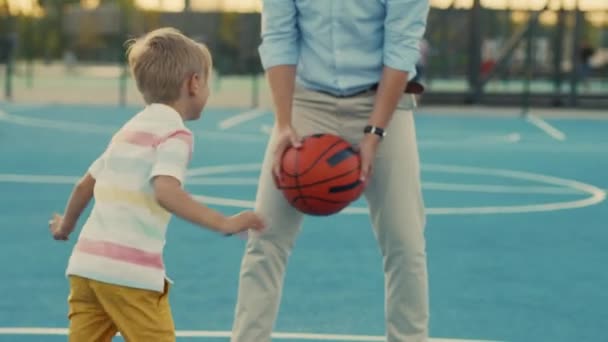 若い男と子供はバスケットボールコートで遊ぶ — ストック動画