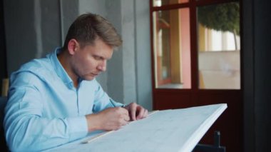 Ofisteki pencerenin yanında genç bir profesyonel çalışıyor.