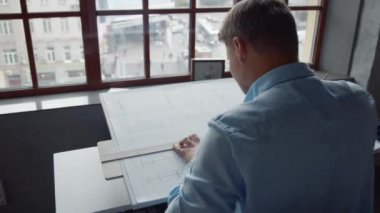 Pencerenin yanında çalışan genç mimar. 