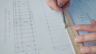Mühendisin elleri bir bina planı çiziyor, ağır çekim.