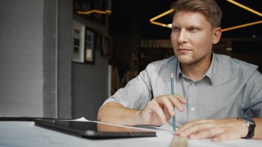 Ofisinde inşaat planı olan bir adam.