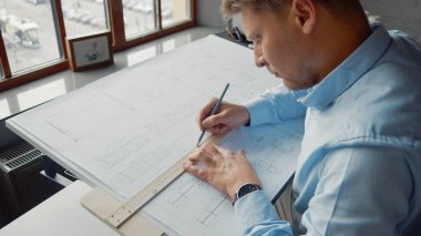 Çalışma masasında inşaat planı olan genç bir mühendis.