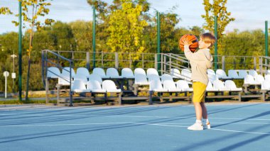 Sahada basketbol oynayan küçük çocuk.