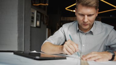 Ofiste inşaat planı olan genç bir adam.