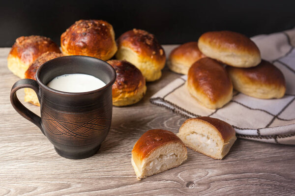 булочки и пироги и глиняный стакан с молоком
