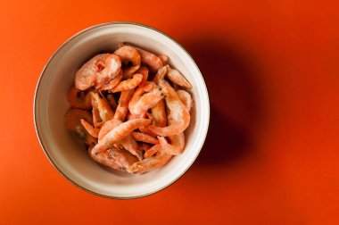 üzerinde kırmızı zemin üzerine metal bir kase çiğ karides