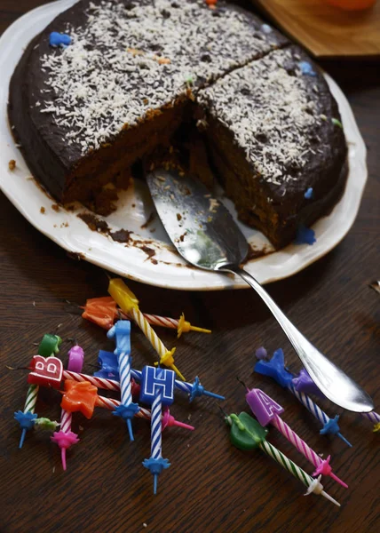 Torta di compleanno mezza mangiata e candele spente — Foto Stock
