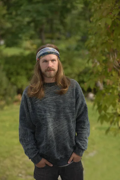 Profile portrait of a young man with long hair and beard in a ba — Stock Photo, Image