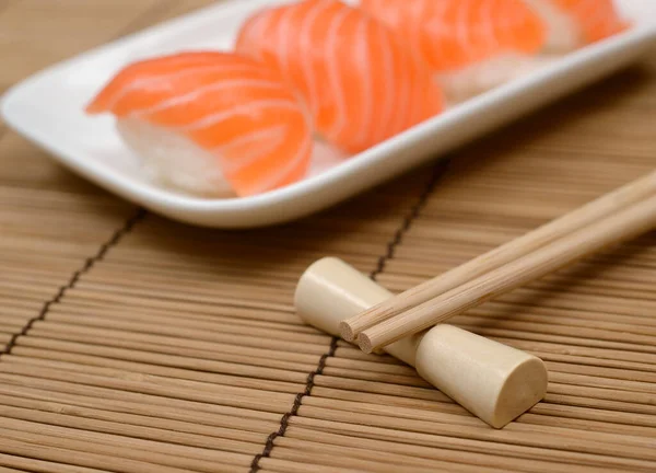 竹席上有鲑鱼的筷子和寿司 — 图库照片