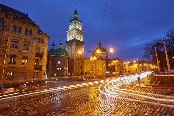 Scenic view on illuminated Assumption Church Bell Tower at twilight with vintage tram on foreground, Lviv, Ukraine. Night winter scenery.