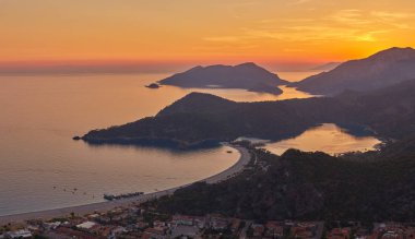 Oludeniz, Türkiye 'de güzel bir gün batımı olan Blue Lagoon' un muhteşem hava manzarası. Plajlı ve dağlı yaz manzarası, yeşil orman, gök mavisi su, kumlu sahil ve açık güneşli bir günde mavi gökyüzü en iyi turist.