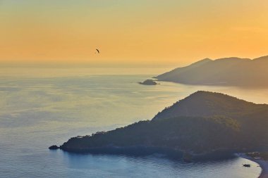 Oludeniz, Türkiye 'de güzel bir gün batımı olan Blue Lagoon' un muhteşem hava manzarası. Plajlı ve dağlı yaz manzarası, yeşil orman, gök mavisi su, kumlu sahil ve açık güneşli bir günde mavi gökyüzü en iyi turist.