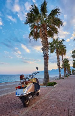 Sandy beach Konyaaltı ve günbatımı, Antalya, Türkiye'nin Akdeniz kıyılarında sırasında retro motorlu scooter