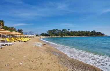 Şemsiye ve boş plaj sandalyeleri yakınındaki mavi deniz suyu, Kemer, Türkiye, Akdeniz sahilde.