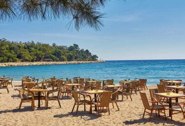 Tables and chairs on terrace in outdoor restaurant with view on Mediterranean sea in Kemer, Turkey. clipart