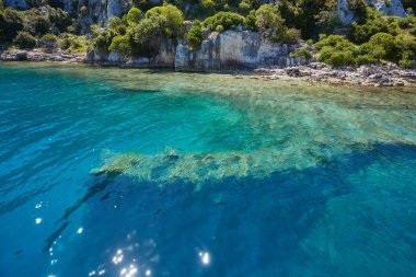 Kekova batık şehir Antalya Kastamonu ilinin turqouise deniz kaya ile ve yeşil çalılar ile denizden Uchagiz bay görünümünde antik kentin su altında görünür kalır.