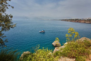 Antalya, Türkiye'de açık günbatımı gökyüzü yüksek dağlardan deniz manzarası timelapse. Deniz ve ön plan çiçekler.