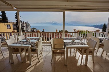 Konyaaltı bölgesinde popüler tatil şehir Antalya, Türkiye, mavi deniz kenarında uçurumun kenarında restoranda. Güneşli bir gün, ufukta yüksek dağlar