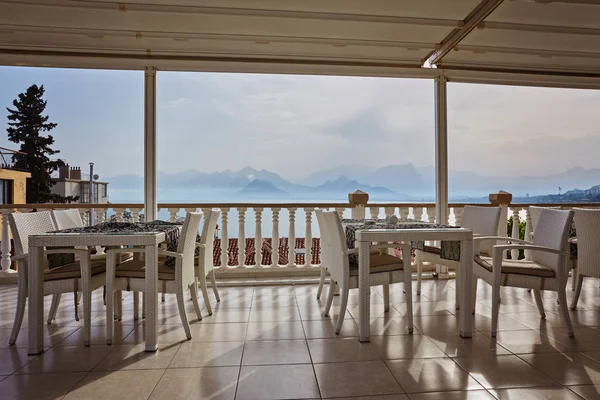 Restaurant at edge of cliff near blue sea in Konyaalti district of popular resort city Antalya, Turkey. Sunny day, high mountains on horizon