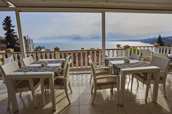 Konyaaltı bölgesinde popüler tatil şehir Antalya, Türkiye, mavi deniz kenarında uçurumun kenarında restoranda. Güneşli bir gün, ufukta yüksek dağlar