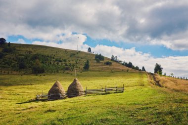dağ otsu çayır saman yığını. güzel kırsal manzara mavi gökyüzü ile yaz aylarında bazı bulutlarda altında
