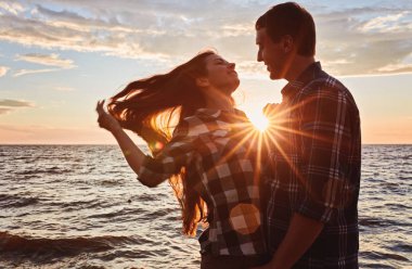 Adam ve kadın doğa gezintisindeler. Aşk ve aşk. Günbatımında öpüşmek.