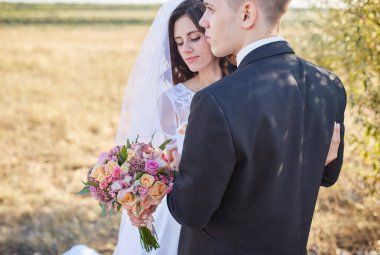 iki sonra düğün kıyafetleri ile bir buket çiçek ve yeşillik ellerinizde