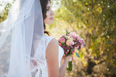 Doğal çiçek çelenk giymiş ve elinde okaliptüs ile altın yaz alanlarında ayakta gülümseyen güzel gelin.