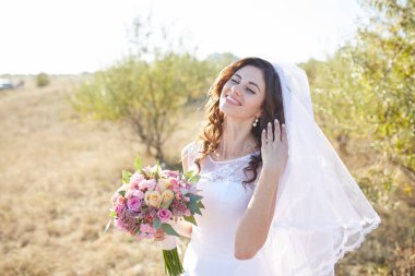 Doğal çiçek çelenk giymiş ve elinde okaliptüs ile altın yaz alanlarında ayakta gülümseyen güzel gelin.