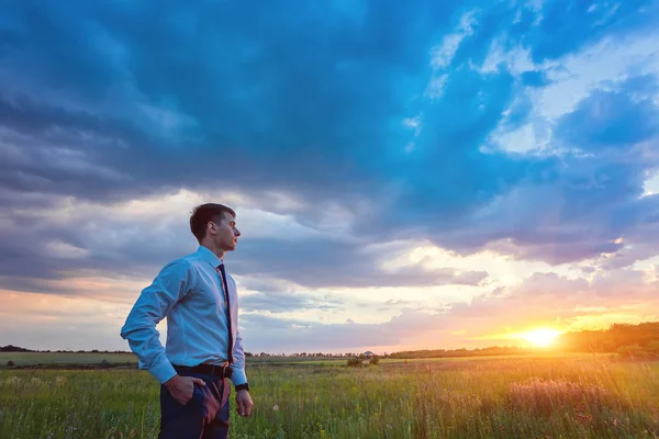 Affärsman som står på fältet innan solnedgången — Stockfoto