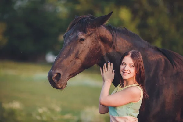 Gyönyörű fiatal női gyaloglás és átölelve vele barna ló — Stock Fotó