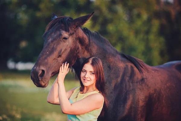 Gyönyörű fiatal női gyaloglás és átölelve vele barna ló — Stock Fotó