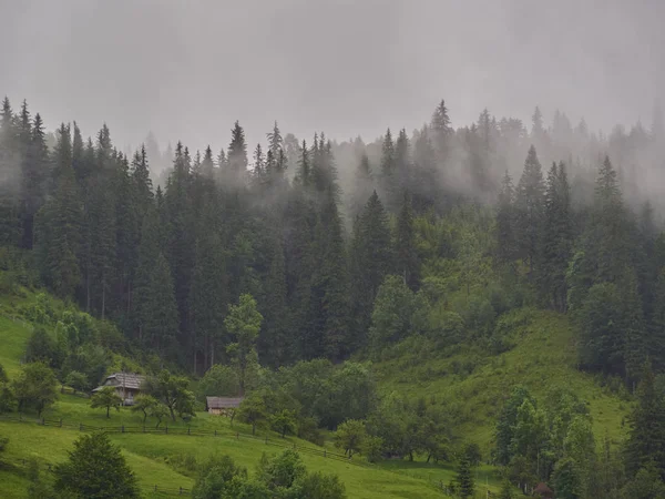 Paisagem montanhosa no nevoeiro. casa nas montanhas . — Fotografia de Stock