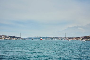Geçen Boğaz Köprüsü boğaz boğaz arka plan ile arka plan bulutlu mavi gökyüzü ve Istanbul, Türkiye'de mavi deniz güneşli bir gemi. Türkiye kavramı mavi.