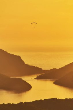 Gün batımında Ölüdeniz, Türkiye'de mavi lagün üzerinde uçan tanımlanamayan bir yamaçparaşütü