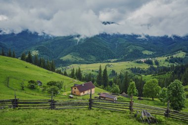 Dağlar yeşil bir çayırda bir ahşap ev. Eski orman yakınlarında bir evi var. Karpat köyün yaşam tarzı.