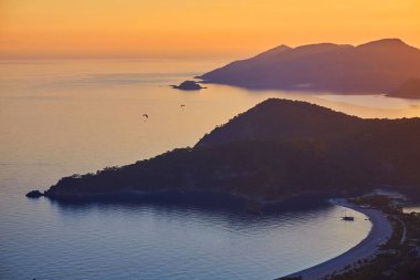 Gün batımında Ölüdeniz, Türkiye'de mavi lagün üzerinde uçan tanımlanamayan bir yamaçparaşütü