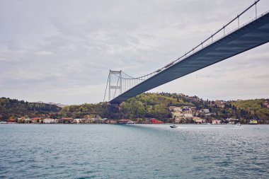 Geçen Boğaz Köprüsü boğaz boğaz arka plan ile arka plan bulutlu mavi gökyüzü ve Istanbul, Türkiye'de mavi deniz güneşli bir gemi. Türkiye kavramı mavi.