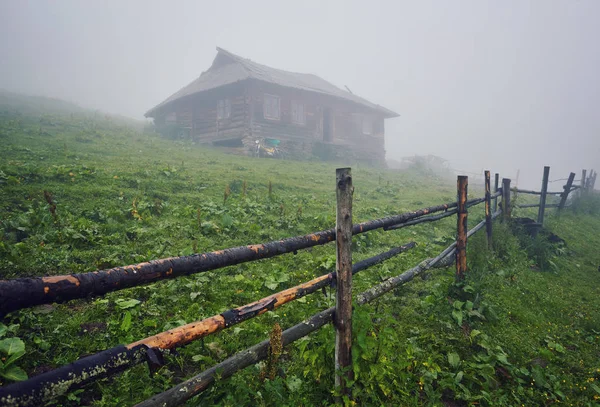 Mountain landscape in the fog. house in the mountains. The old spooky house on the land of nowhere. Wooden house in the middle of the barren land. Scenic retro landscape.