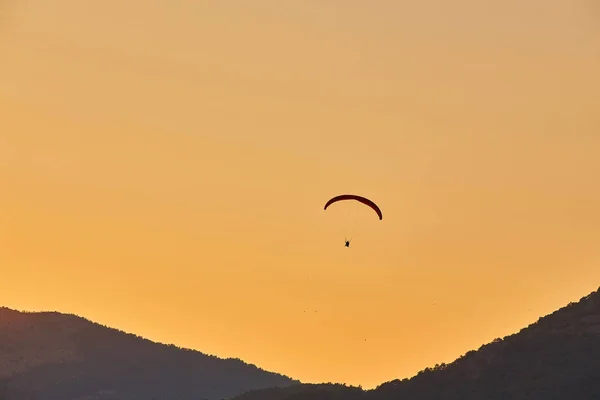 Siklóernyő Silhouette Repül Ködös Hegyvidéki Völgyben Gyönyörű Meleg Naplemente Színeiben — Stock Fotó