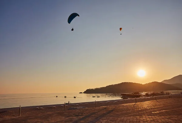 Paraglider silhouette flying over misty mountain valley in beautiful warm sunset colors - sport, active wallpapers full of freedom. Background with space for your montage