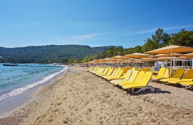 Şemsiye ve boş plaj sandalyeleri yakınındaki mavi deniz suyu, Kemer, Türkiye, Akdeniz sahilde.