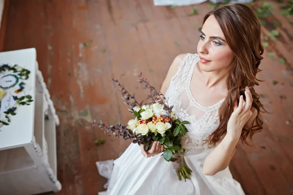 Bela noiva em um vestido de noiva em um estúdio elegante brilhante. Casamento em estilo europeu. Decoração e buquê na mão . — Fotografia de Stock