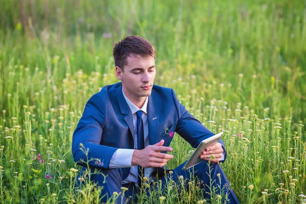 Obchodník, který sedí ve venkovním prostředí a používá tablet — Stock fotografie